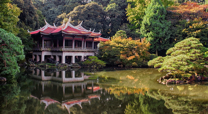 Traditional Japanese Pavilion in Autumn Garden with Pond Reflection