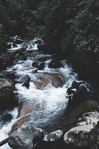 Hiker resting by a rushing forest stream