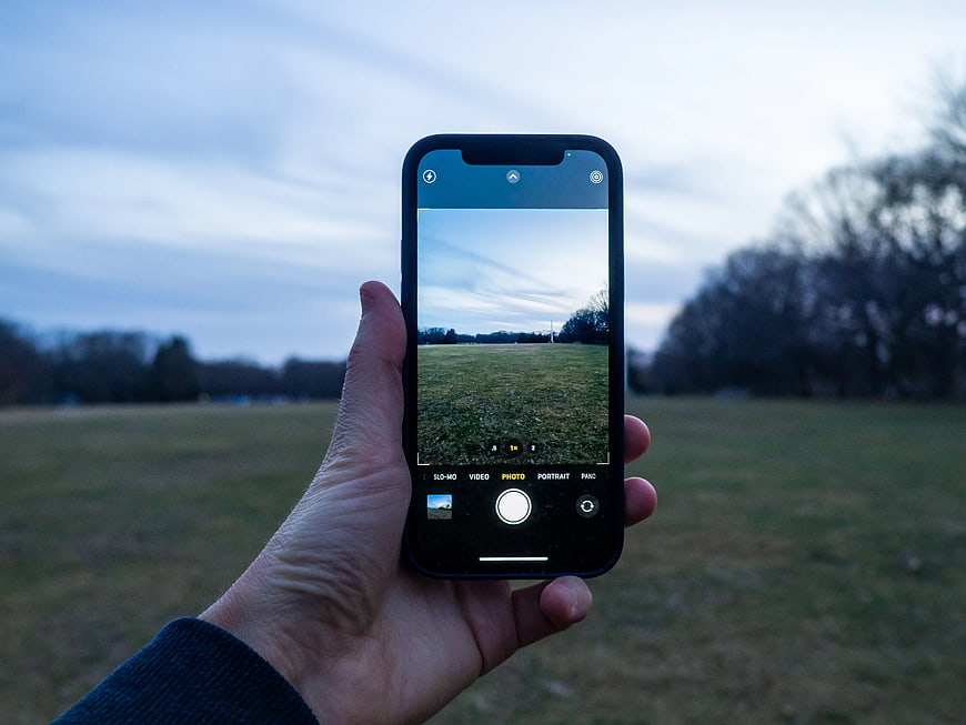 Hand Holding Smartphone Taking Photo of Park Landscape