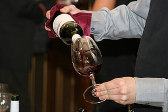 Sommelier pouring red wine into a glass with a cloth