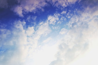 Bright blue sky with fluffy white clouds and sunlight