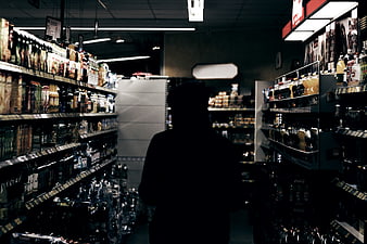 Silhouette of person in dark grocery store aisle