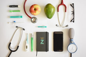 Medical flat lay with stethoscopes, syringes, apple, avocado, and smartphone