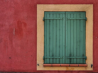 Green wooden shutters on a red textured wall