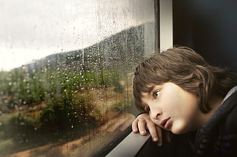 Sad boy looking out rainy train window