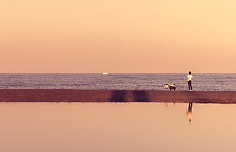 Silhouette of people on beach at sunset with water reflection