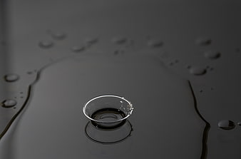 Close-up of water droplets on a dark reflective surface