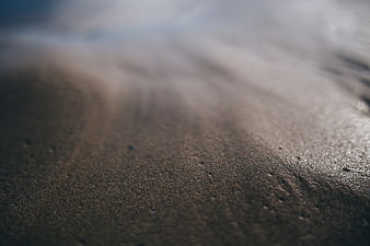 Close-up of wet sand texture on a beach with blurred background