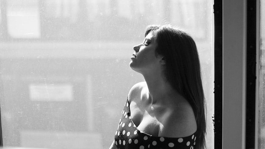 Black and white portrait of woman in polka dot dress by window