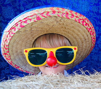 Child in straw hat and clown nose with sunglasses