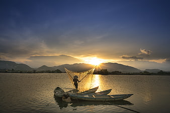 Fisherman Casting Net on Boat at Sunrise in Vietnam