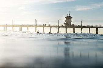 Surfers waiting in ocean water with pier in background