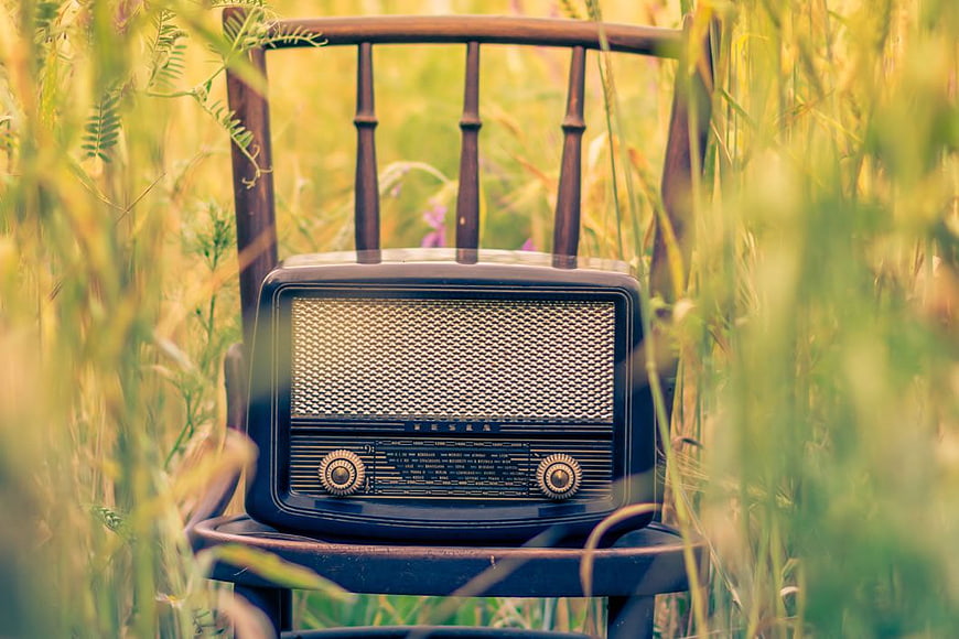Vintage Radio on Wooden Chair in Grassy Field
