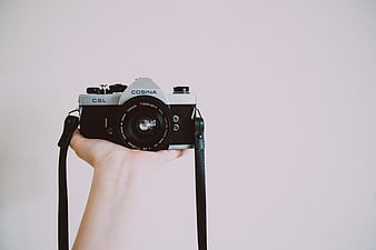 Hand Holding Vintage Cosina Camera on Minimal Background