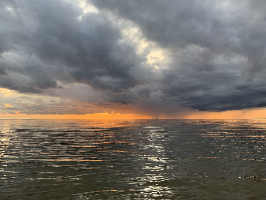 Dramatic sunset over ocean with storm clouds and rain
