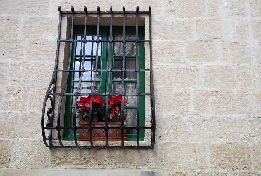 Traditional stone house window with red flowers