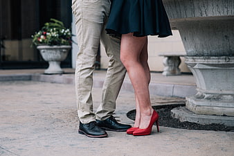 Couple legs with red heels and black shoes on city pavement
