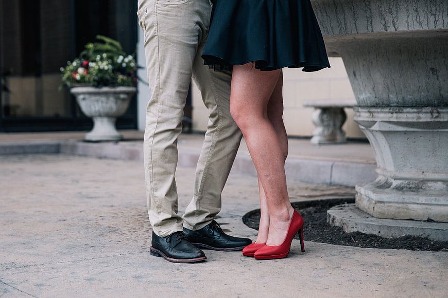 Couple legs with red heels and black shoes on city pavement