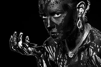 Dramatic black and white portrait of woman covered in glossy black substance