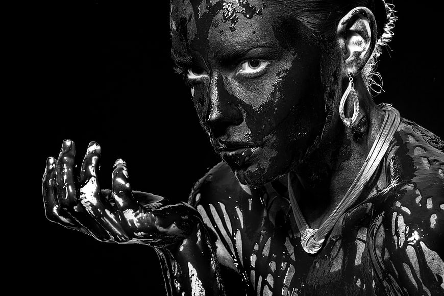 Dramatic black and white portrait of woman covered in glossy black substance
