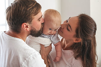 Happy Parents Kissing Baby in White T-Shirts