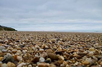 Low angle view of pebble beach with blurred ocean horizon