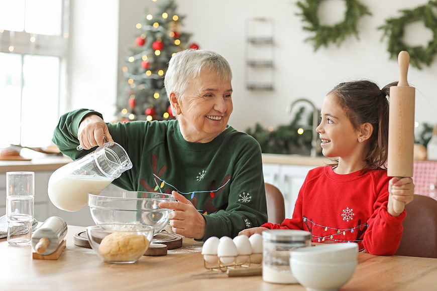 Grandmother and granddaughter baking cookies together in a kitchen at Christmas