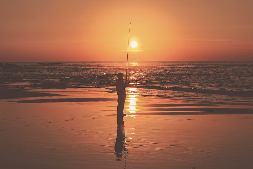 Silhouette of Man Fishing on Beach at Sunset