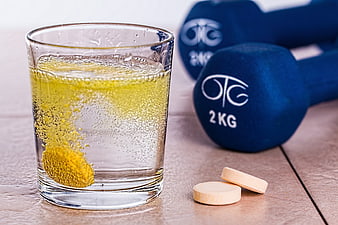 Effervescent Vitamin Tablet Dissolving in Water with Dumbbells