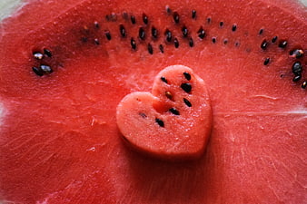 Heart-shaped watermelon slice on red fruit background