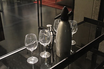 Modern bar setup with wine glasses and seltzer bottle on black table