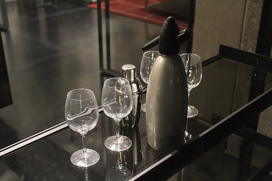 Modern bar setup with wine glasses and seltzer bottle on black table