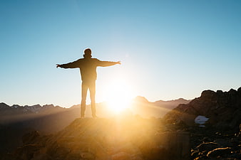 Silhouette of Man Standing on Mountain Peak at Sunrise