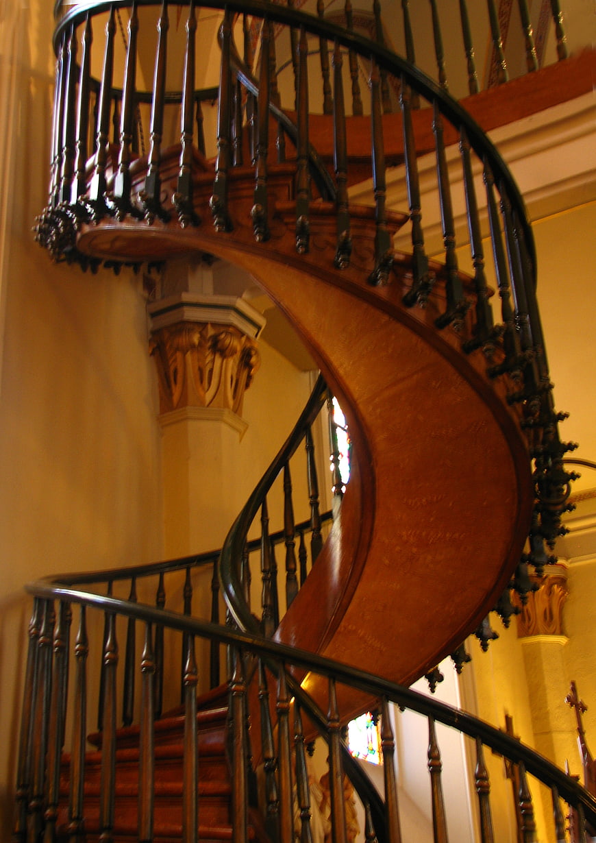 Elegant wooden spiral staircase with black iron railing