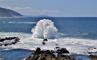 Powerful ocean wave crashing against rocky coastline