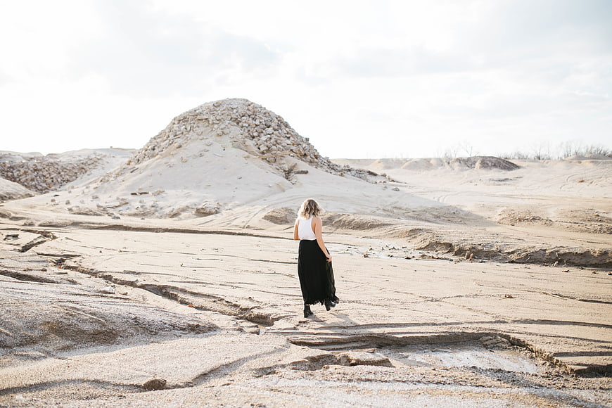 Woman in Black Skirt Walking Through Arid Desert Landscape