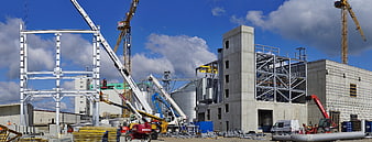 Industrial construction site with cranes and steel framework