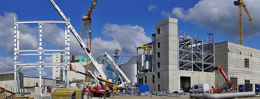 Industrial construction site with cranes and steel framework