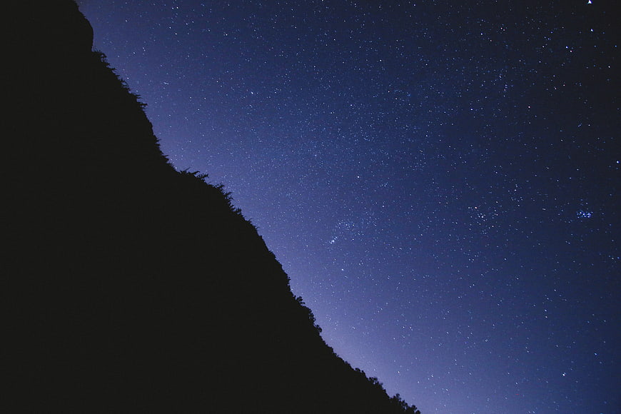 Silhouette of mountain ridge against starry night sky