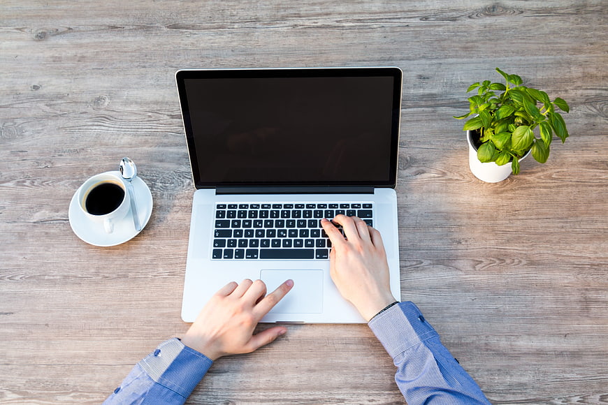 Top View of Hands Typing on Laptop with Coffee and Plant