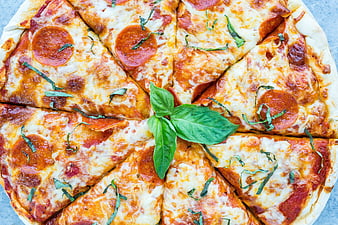 Fresh pepperoni pizza with basil leaves overhead