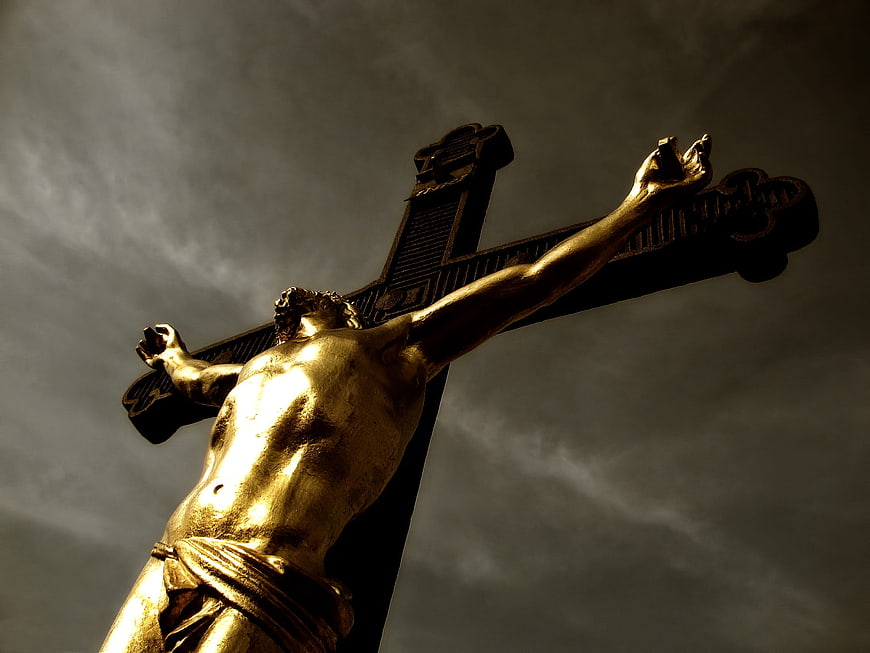 Golden Crucifix Statue Against Dramatic Cloudy Sky