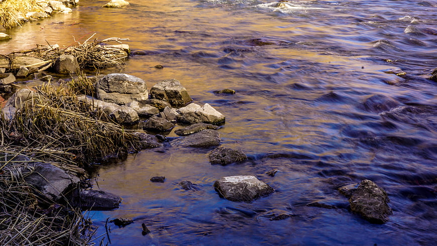 Flowing River with Rocks and Golden Reflections