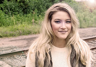 Portrait of smiling blonde woman outdoors near train tracks