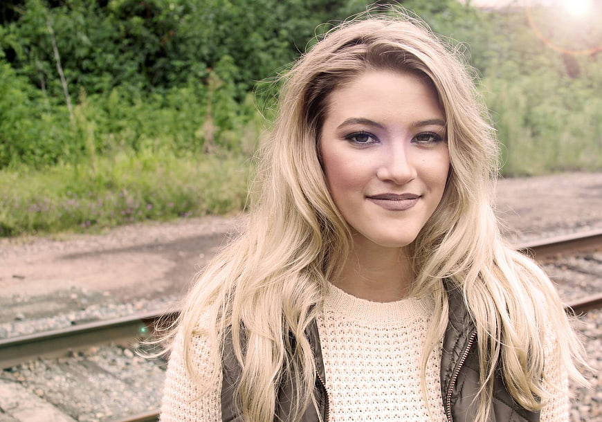 Portrait of smiling blonde woman outdoors near train tracks