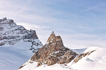 Snowy mountain peak with summit building and blue sky