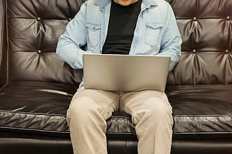 Man working on laptop sitting on leather sofa