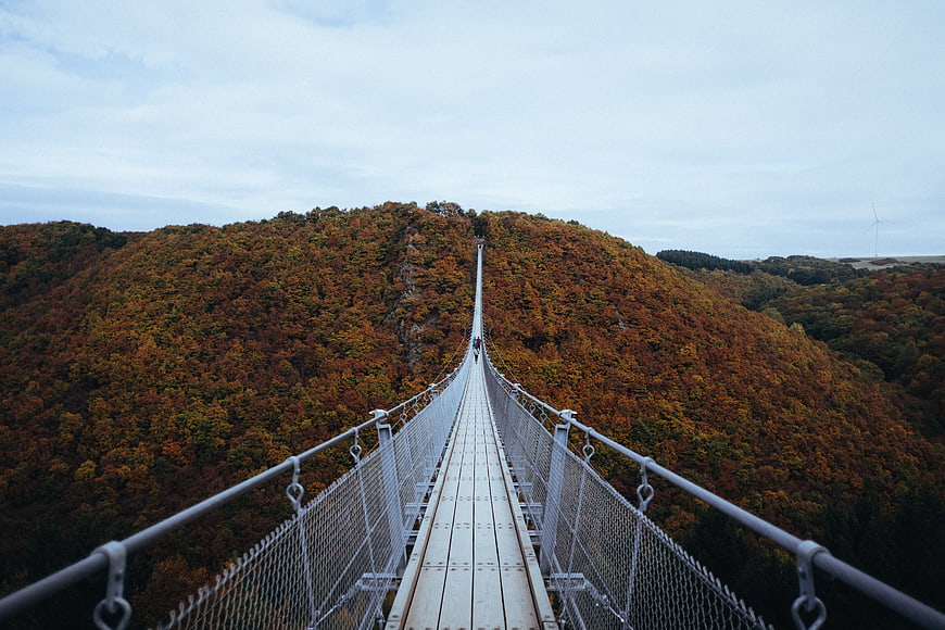 Suspension bridge crossing autumn forested mountain ridge
