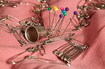 Sewing Thimble, Safety Pins, and Colorful Straight Pins on Pink Fabric