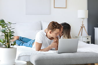 Young couple watching laptop together on bed in bedroom
